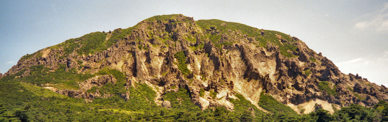 漢拏山西方，웟세오름北側よりの望む漢拏山西北壁西側斜面，ここは漢拏山粗面岩からなり，風化が進む灰白色，灰緑色の斑晶質の岩石である
